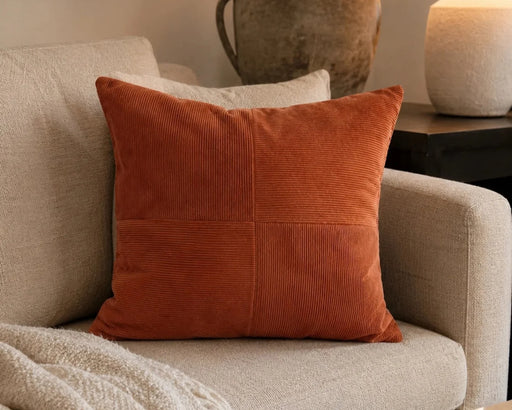 Coussin décoratif JULES en velours rouille posé sur un sofa beige